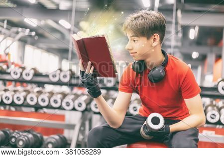 Young Man In Sports Clothes And Headphones Works With Dumbbells In The Gym, Reads A Book With Surpri