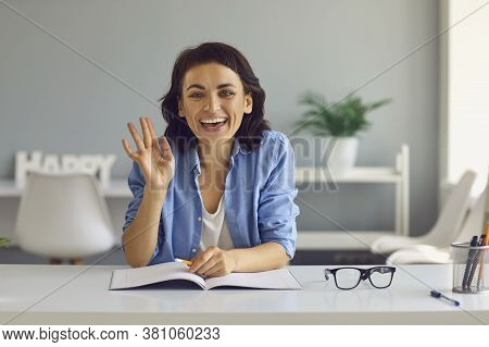 Young Smiling Woman Looking At Camera And Greeting People Online At Home