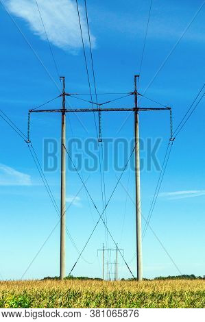 High Voltage Poles With Wires In A Rural Field With Corn