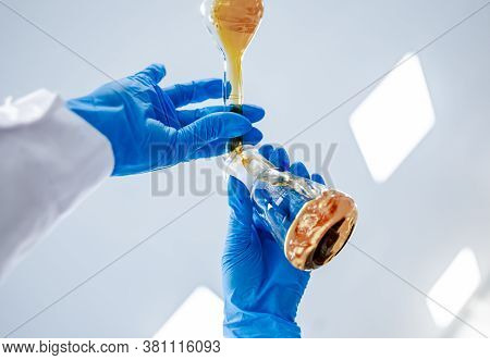 Flasks With Brown Liquid In Scientist Hands With Dropping Chemical Liquid To Test Tubes, Science And