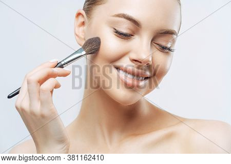 Cropped Shot Of Positive European Woman With Healthy Soft Skin, Uses Cosmetic Powder Brush, Applies 