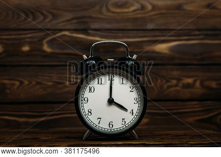 Clock On A Wooden Background. The Clock Shows The Time Of Four O'clock In The Afternoon. The Clock S