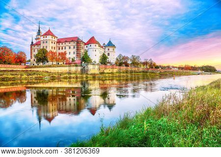 Fantastic Morning View Of Hartenfels Castle On Banks Of The Elbe. Dramatic Sunrise. Location: Torgau