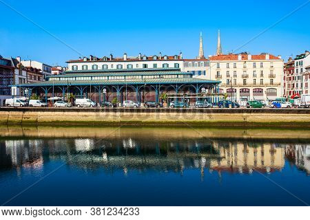 Main Public Market And Colorful Houses At The Nive River Embankment In Bayonne Town In France