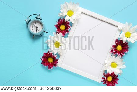 Square White Frame With White And Red Flowers And Blue Alarm Click On Blue Background. View Top. Che