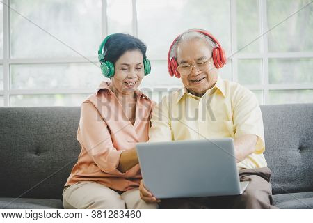 Happy Elderly Couple Is Watiching And Listening To Music Movie From Laptop Computer With Colorful He