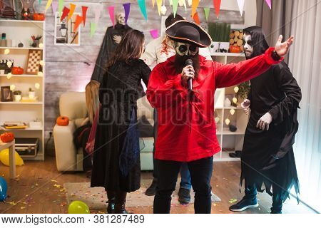 Attractive Man Dressed Up Like A Pirate Doing Karaoke At Halloween Party With His Friends.