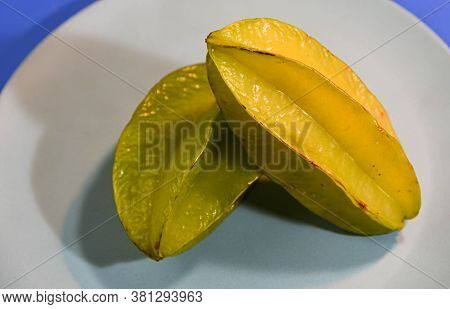 Two Carambola Fruits On Green Color Plate On Blue Background