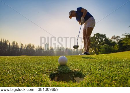 Asian Woman Golfer Action To Win After Long Putting Golf Ball On The Green Golf. Morning Time.