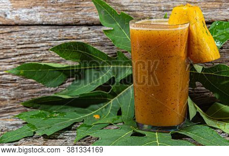 Papaya Juice In A Setting With Fresh Fruits On A Wooden Background.