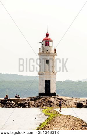 Vladivostok, Russia - July 30, 2015: People Walking Near The Lighthouse. The Old Japanese Lighthouse