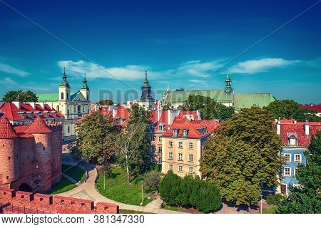 Warsaw, Poland Summer View Of Barbican Or Barbakan Wall And Old Town Houses With Green Trees And Blu