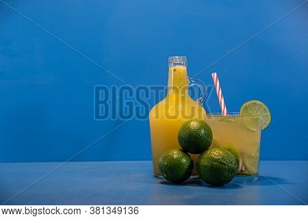 Lemonade And Thaiti Lemon Juice (citrus × Latifolia) In Glass Bottle On Blue Background