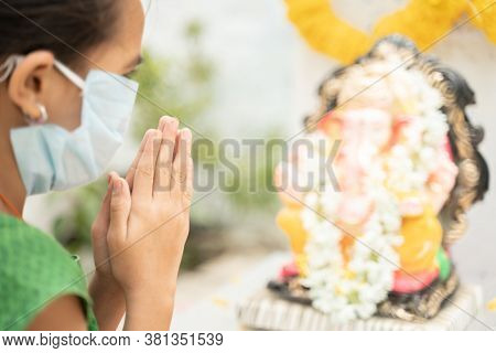 Girl Kid In Medical Mask Praying By Closing Eyes In Front Of Lord Ganesha During Ganesha Or Vinayaka