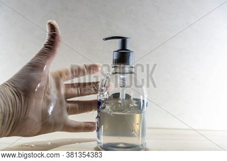 Human Hand With Disposable Glove In Motion To Hold Alcohol Gel In Covid 19 Prevention