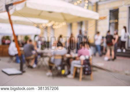 Blurred Background With Group Of Peolple Sitting At The Cafe Veranda Outside.
