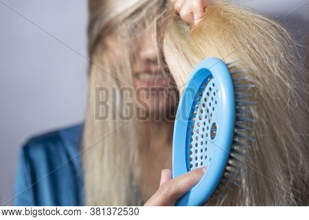 Blonde Combs Her Hair After Shampooing. On A Gray Background. Clean Dry Hair, Healthy, No Problem, C