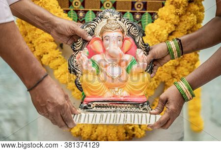 Senior Couples Brought God Ganesha Idol And Placing On Decorated Stage At Home During Vinayaka Chatu