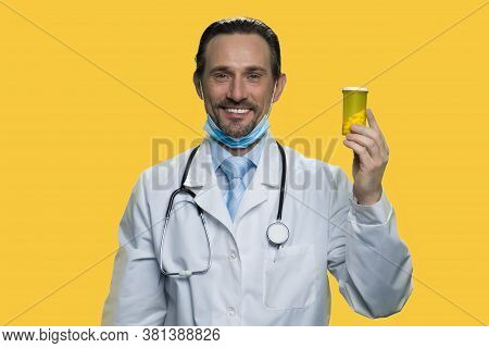 Happy Mature Doctor Showing Bottle Of Pills. Smiling Male Practitioner Holding Jar With Pills Agains
