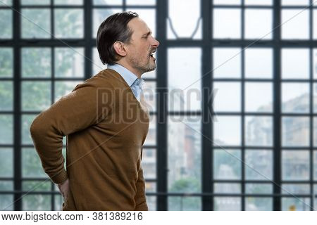 Mature Caucasian Man Suffering From Backache. Side View Of Stressed Male Employee Suffering From Bac