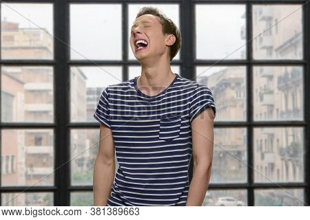 Portrait Of Expressive Desperate Teen Boy. Depressed Teenage Boy Is Crying On Windows Background. St
