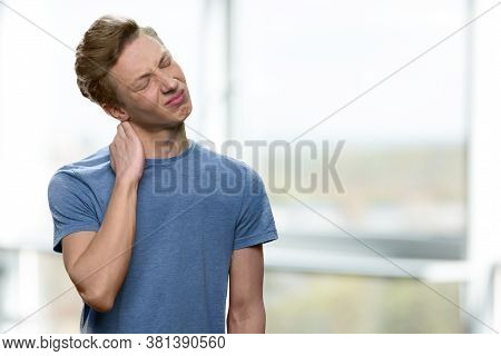 Stressed Teenage Boy Suffering From Neck Pain. Portrait Of Unhappy Teenager Having Bad Neck Ache And