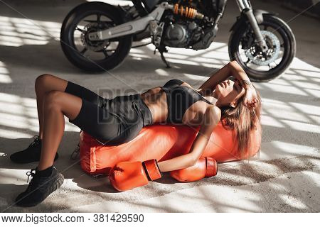 Pretty And Attractive Sportswoman Posing In A Light Studio Lying On The Floor With A Large Orange Pu