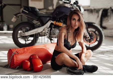 Sexy And Attractive Sportswoman Posing In A Light Studio Lying On The Floor With A Large Orange Punc