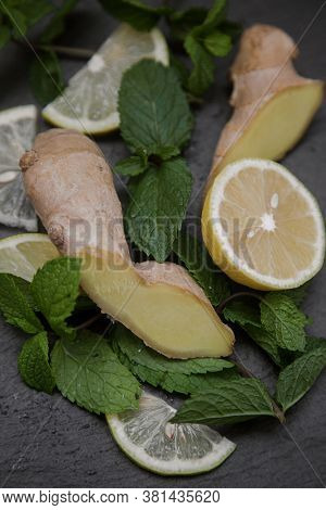 Sliced Lemon And Ginger Root With Mint Sprigs On A Dark Background.