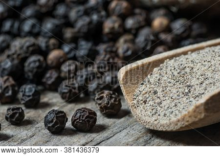 Heap Of Black Pepper And Black Pepper Powder In Wooden Spoon, Milled Peppercorns On Wooden Backgroun