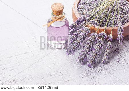 Glass Bottle Of Lavender Essential Oil With Fresh Lavender Flowers And Dried Lavender Seeds On White
