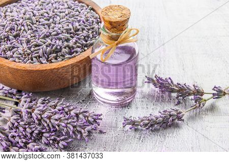 Glass Bottle Of Lavender Essential Oil With Fresh Lavender Flowers And Dried Lavender Seeds On White