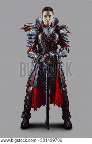 Portrait Of A Medieval Female Knight In Armour With A Sword In Hand. Isolated Over Grey Background.