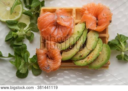 Waffle With Slices Of Salted Salmon And Avocado. The Concept Of A Healthy Breakfast.