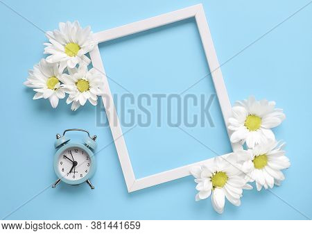 Square White Frame With White And Red Flowers And Blue Alarm Click On Blue Background. View Top. Che