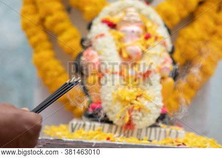 Hands Holding Or Offering Incense Or Agarbatti Stick In Front Of Lord Vinayaka Or Ganesha While Pray