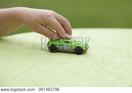 Umea, Norrland Sweden - June 28, 2020: A Child Plays With A Toy Car On A Green Tablecloth