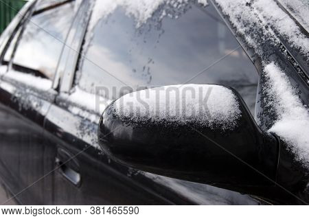 Side Of A Snowy Black Car With Mirror On A Cold Winter Morning, Horizontally Framed Picture.