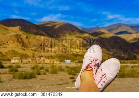 Female Feet In Sierra Alhamilla Landscape, Spain. Caravan At El Chorillo Movie Location In The Backg