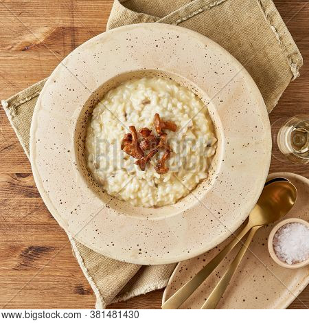 Risoto With Chanterelle Mushrooms In Large Plate. Traditional Italian Dish. Wooden Old Table