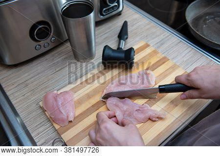 Female Hands Cut Chicken Fillet On Wooden Board With A Knife
