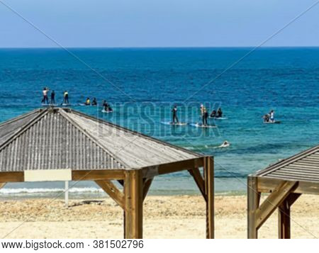 Sea Beach At Sunlight Day. Stand Up Paddle Boarding. Young People Floating On A Sup Boards. Blurred 