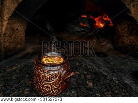 Cooking Traditional Baked Soup In A Clay Pot In The Hearth, Over An Open Fire In A Cafe. Lamb Guvech
