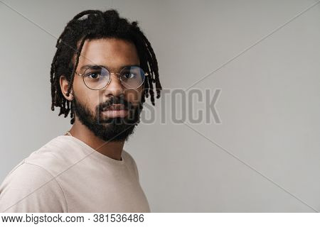 Image of concetrated african guy posing isolated over grey wall background in eyeglasses