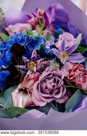 Close-up Bouquet Of Flowers, Packed In Purple Paper On A Light Background. Bouquet Of Eucalyptus, Ca