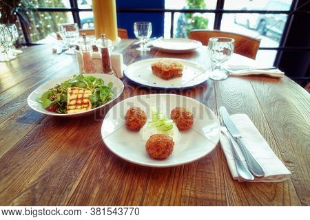 Set of three Greek dishes - fried Saganaki cheese, moussaka and zucchini fritters, toned