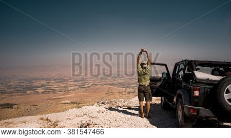 Tourist on the Break from a Long Ride. Standing near the Car and Stretching. Enjoying Amazing View of Bekaa Valley. Active Summer Vacation. Road Trip. Freedom Concept. Lebanon