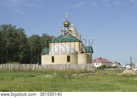 Construction, Renovation Of A Small Orthodox Church With Golden Domes, Wooden Scaffolding. Summer In