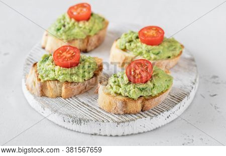 Avocado Toasts With Tomatoes On The Wooden Board