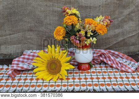 Against The Background Of Jute Fabric, On A Colored Napkin In A Vase, There Is A Bright Bouquet Of T